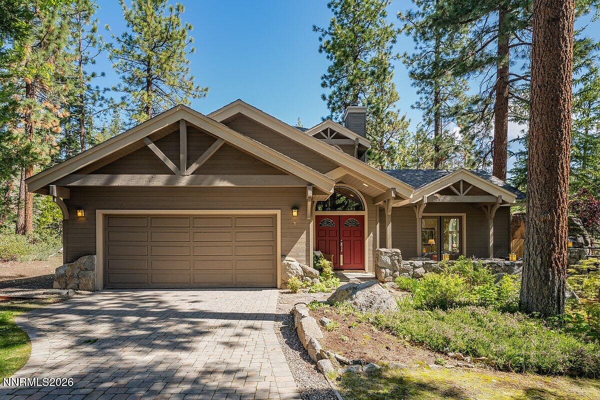 Front elevation of 1 Kelly Cir, a Craftsman-influenced mountain home with peaked timber gables and red double doors set among towering Tahoe pines and granite boulders in Uppaway Estates, Glenbrook